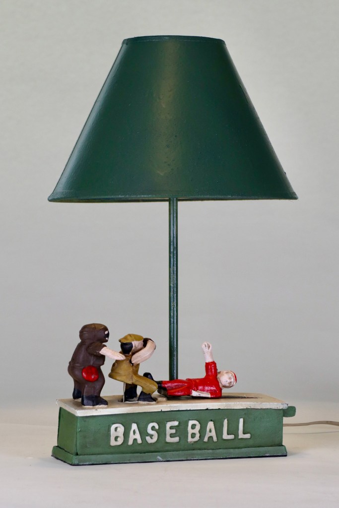 metal bank with figurines of an umpire behind a catcher tagging a sliding player at home base