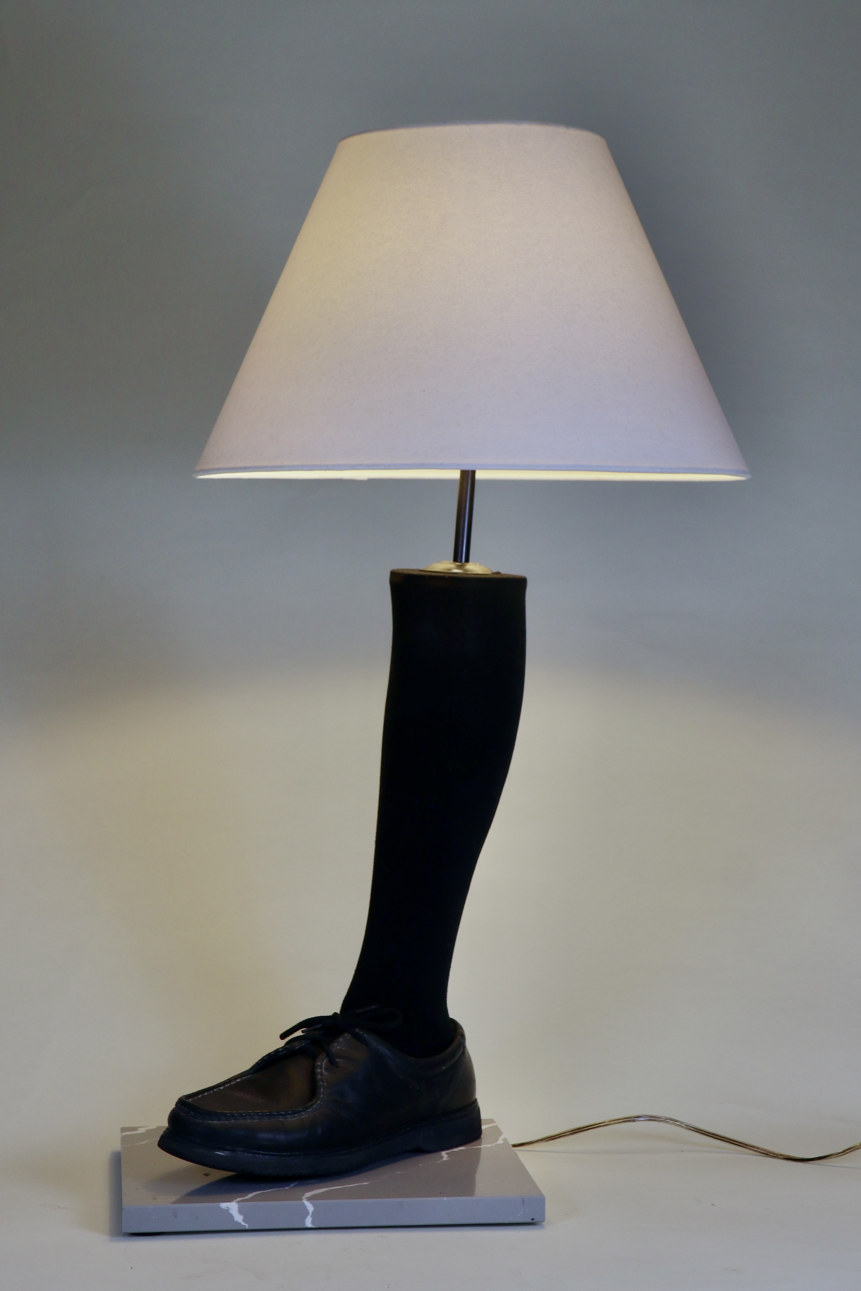 Lamp made from the calf of an artificial leg with black sock and shoe.