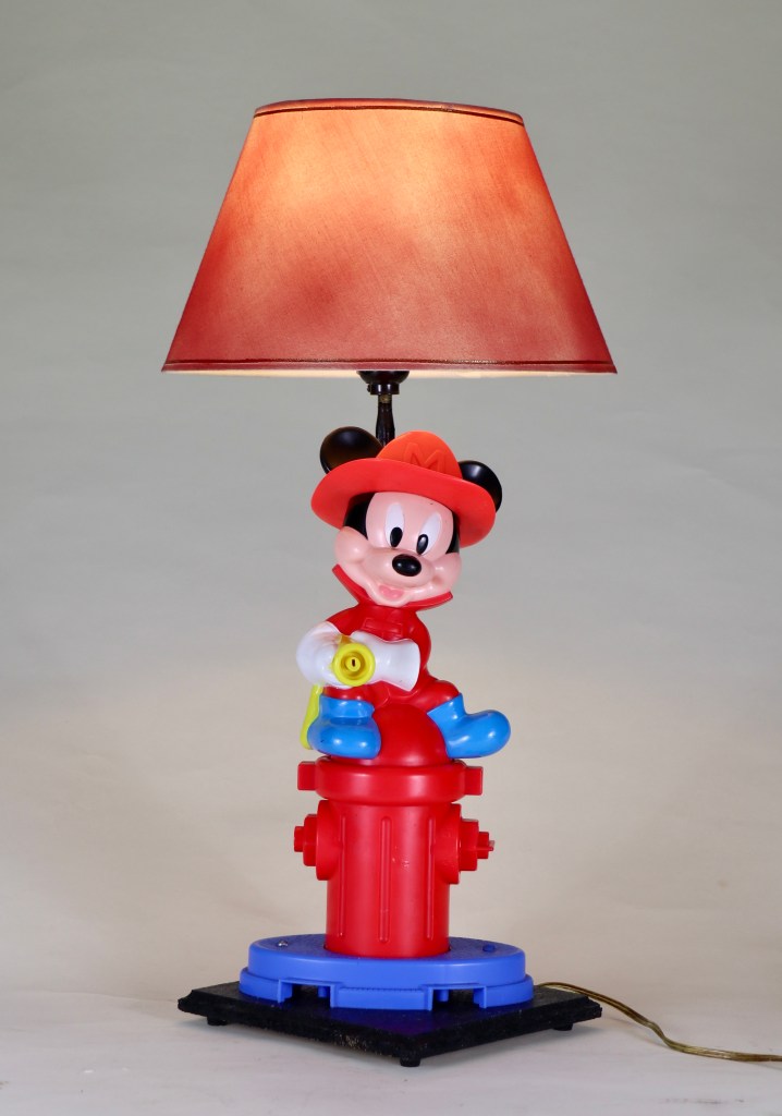 plastic Mickey Mouse in firefighter attire atop red fire hydrant